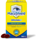 A box of MacuShield Original+ food supplement for eye health, shown on a white background with two dark red capsules in front. The packaging is predominantly bright yellow with blue and white graphics, featuring an eye illustration and text indicating a 90-day pack.